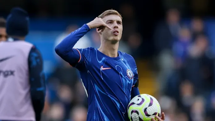 Cole Palmer holding the match ball after scoring a hat-trick in a Premier League game, smiling with pride.