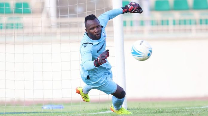 Levis Opiyo diving to save a shot during a football match, fully stretched with focus and determination.