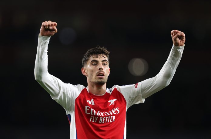 Arsenal Kai Havertz celebrating with arms raised, smiling and running towards the corner flag after scoring a header for Arsenal against PSG in a Champions League match at the Emirates Stadium.