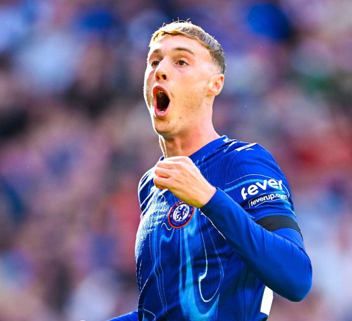 Palmer in a blue jersey celebrating with a determined expression, fist clenched.