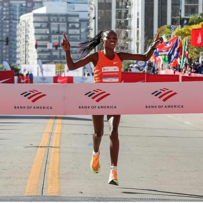 Chepng'etich crossing the finish line at the 2024 Chicago Marathon, raising her hands in victory after breaking the women's world marathon record.