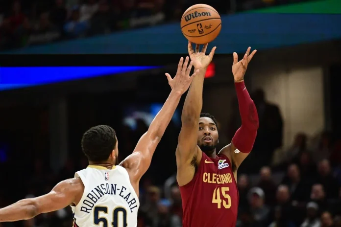 NBA Nov 20, 2024; Cleveland, Ohio, USA; Cleveland Cavaliers guard Donovan Mitchell (45) shoots over the defense of New Orleans Pelicans forward Jeremiah Robinson-Earl (50) during the first half at Rocket Mortgage FieldHouse.