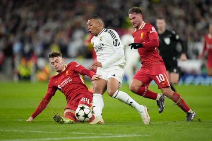 Liverpool Conor Bradley makes a crucial tackle on Kylian Mbappé during a high-stakes Champions League clash, with Alexis Mac Allister providing defensive support.