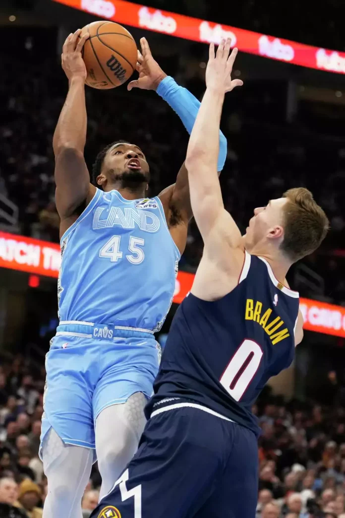 Cleveland Cavaliers guard Donovan Mitchell (45) shoots over Denver Nuggets guard Christian Braun (0) in the first half of an NBA basketball game, Thursday, Dec. 5, 2024, in Cleveland.