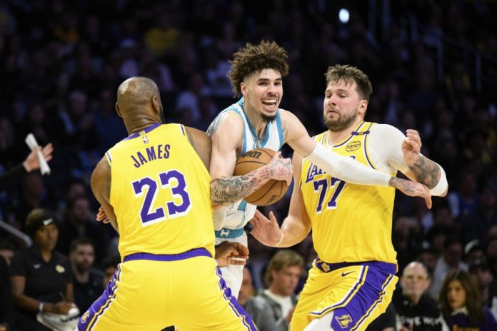 Charlotte Hornets guard LaMelo Ball, center, is contested by Los Angeles Lakers forward LeBron James (23) and Los Angeles Lakers guard Luka Doncic (77) during the first half of an NBA basketball game Wednesday, Feb. 19, 2025, in Los Angeles. (AP Photo/William Liang)