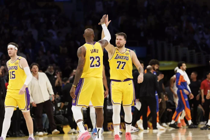 NBA:Lakers stars LeBron James, left, and Luka Doncic celebrate after Doncic hit an important three-pointer in overtime of a 113-109 win over the New York Knicks at Crypto.com Arena on Thursday night.(Gina Ferazzi / Los Angeles Times)