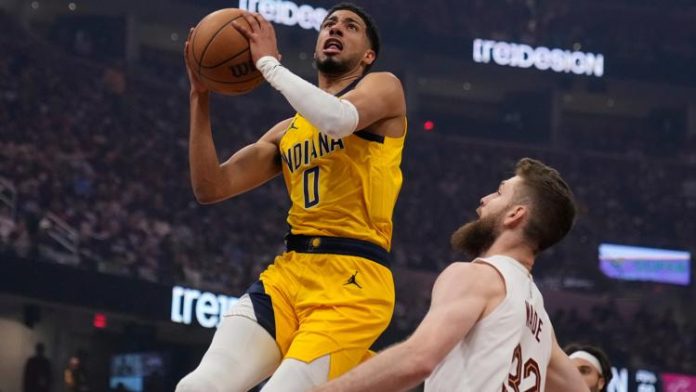 Indiana Pacers' Tyrese Haliburton (0) goes to the basket in front of Cleveland Cavaliers' Dean Wade (32). (AP Photo/Sue Ogrocki)